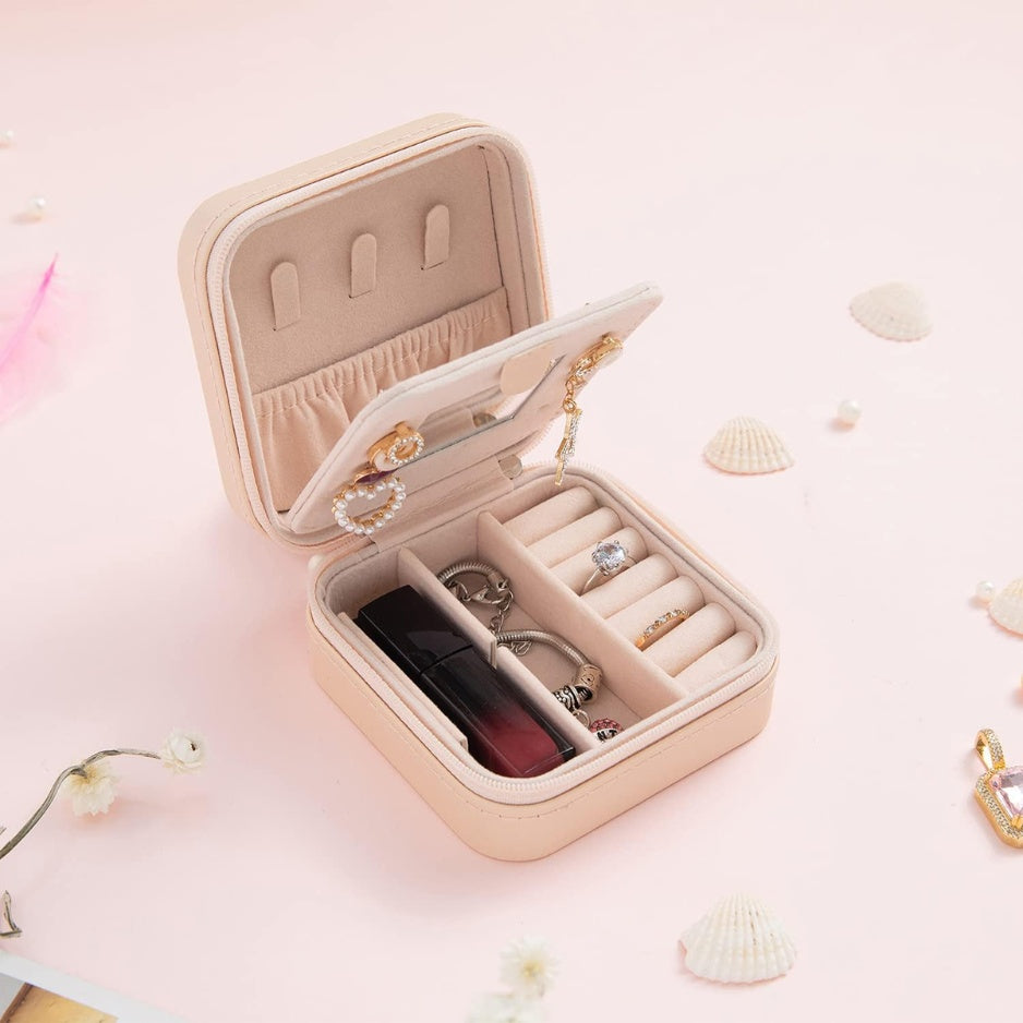 Pink travel jewelry case open to show its mirror and jewelry storage compartments.