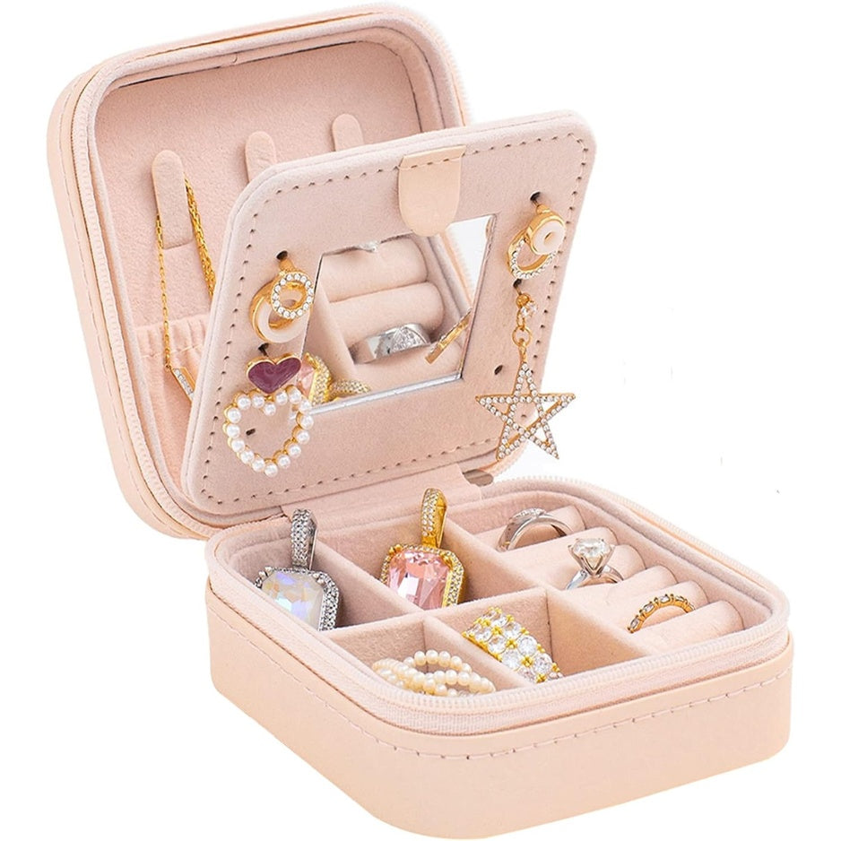 Open pink travel jewelry case with mirror, ring slots, and divided compartments.