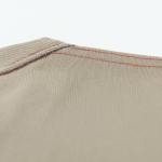 Close-up of red double-stitched shoulder seam on beige twill fabric