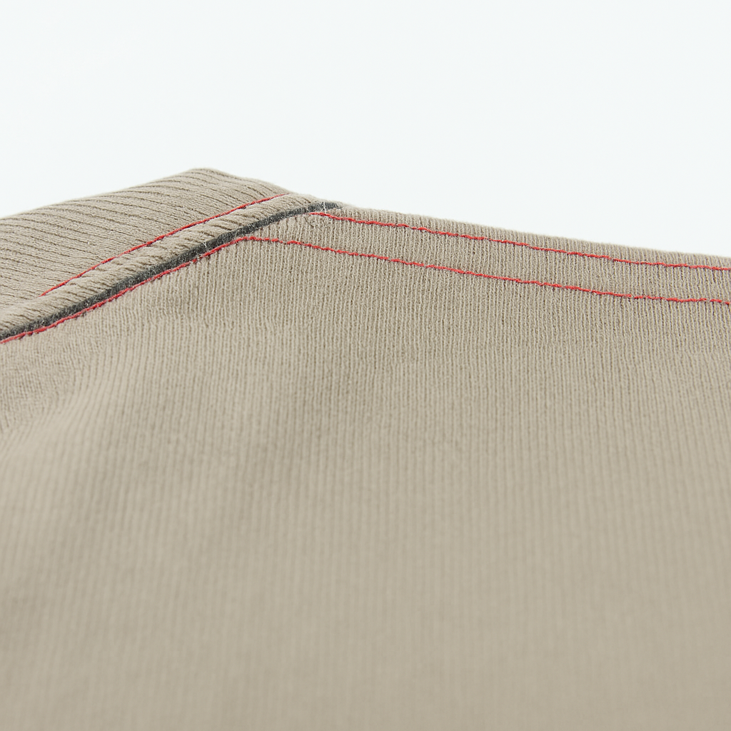 Close-up of red double-stitched shoulder seam on beige twill fabric