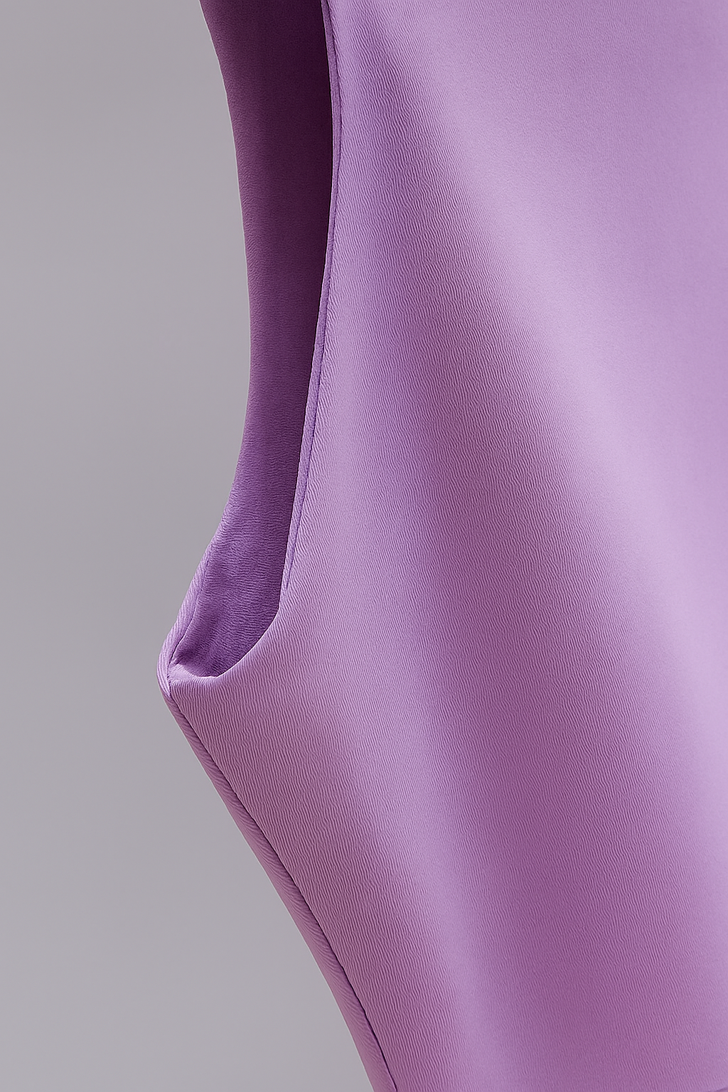 Close-up of a lavender sleeveless crop top showing armhole and side seam detail against a gray background.