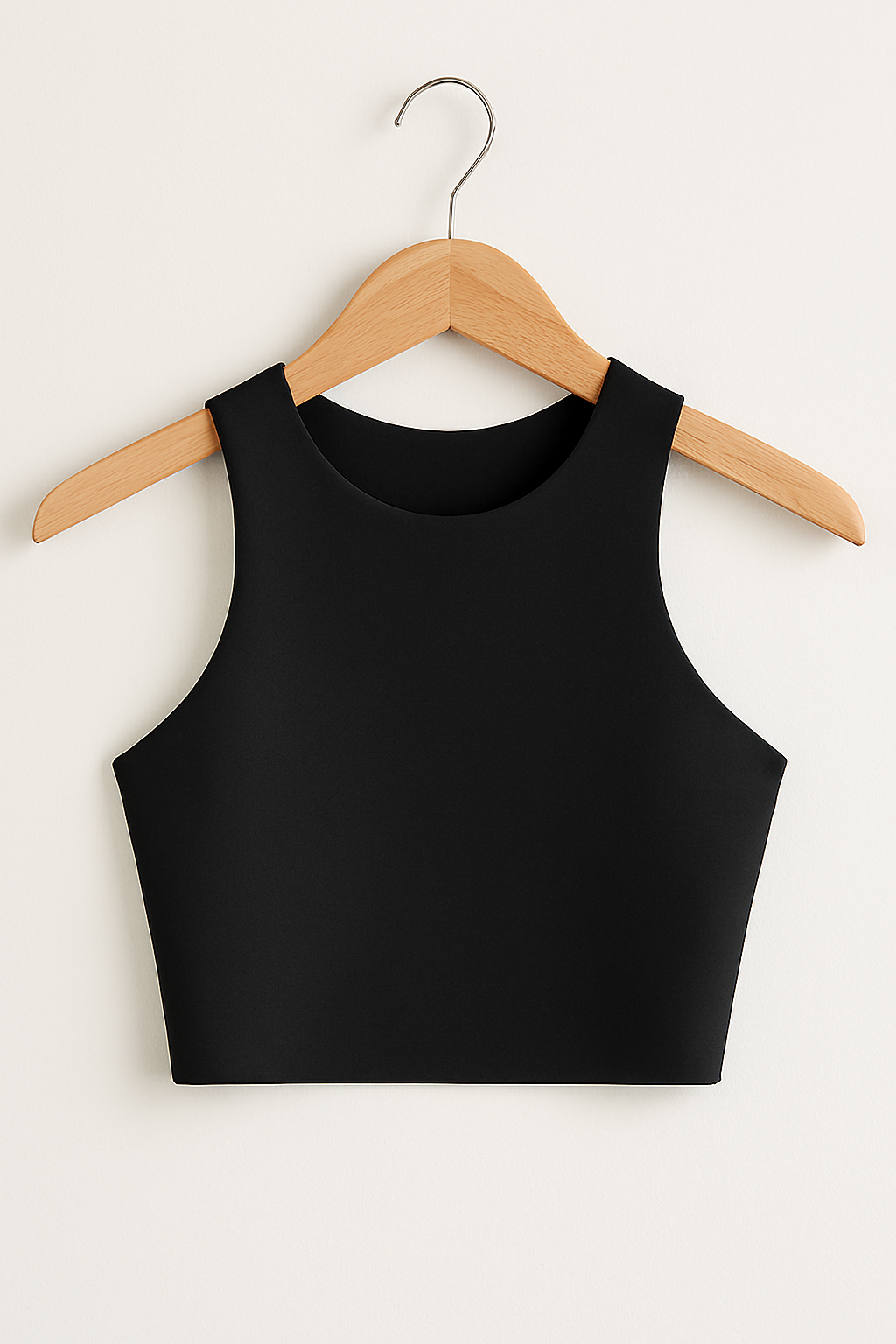 Black sleeveless crop top on wooden hanger against white background.