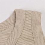 Close-up of beige ribbed knit fabric showing neckline and shoulder stitching.