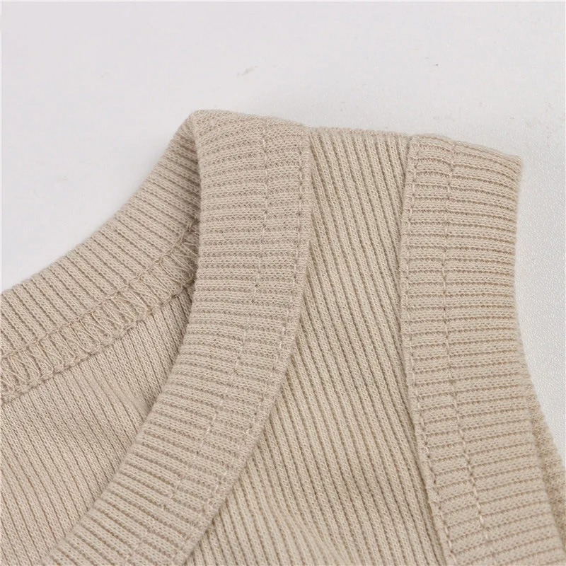 Close-up of beige ribbed knit fabric showing neckline and shoulder stitching.