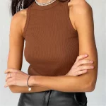 Person wearing a sleeveless ribbed brown top and black pants, accessorized with a bracelet and necklace.