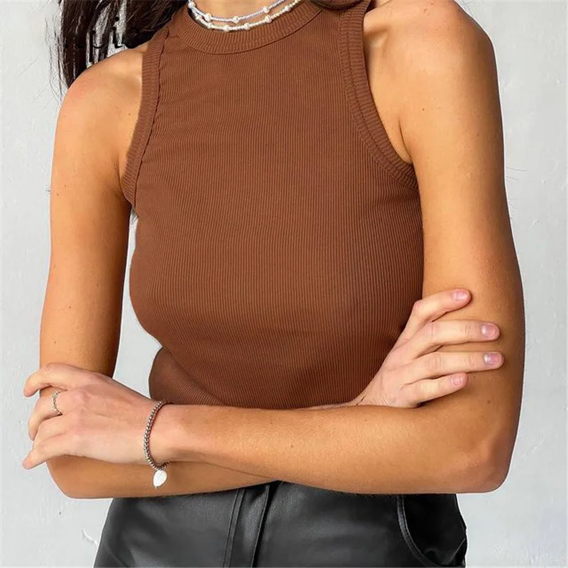 Person wearing a sleeveless ribbed brown top and black pants, accessorized with a bracelet and necklace.