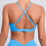 Back view of model wearing cobalt blue halter bra with thin crisscross straps and matching leggings
