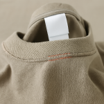 Beige crewneck collar with blank white label and red double stitching detail.