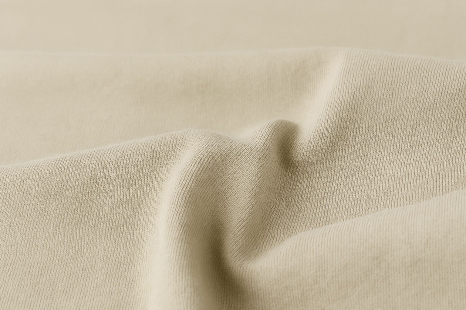 Close-up of beige knit fabric with soft folds and fine texture.